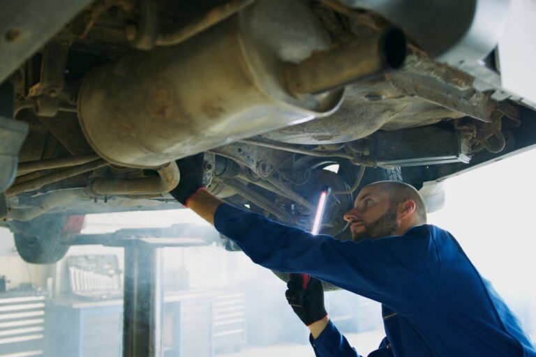 Man in Blue Coverall Checking Under A Vehicle