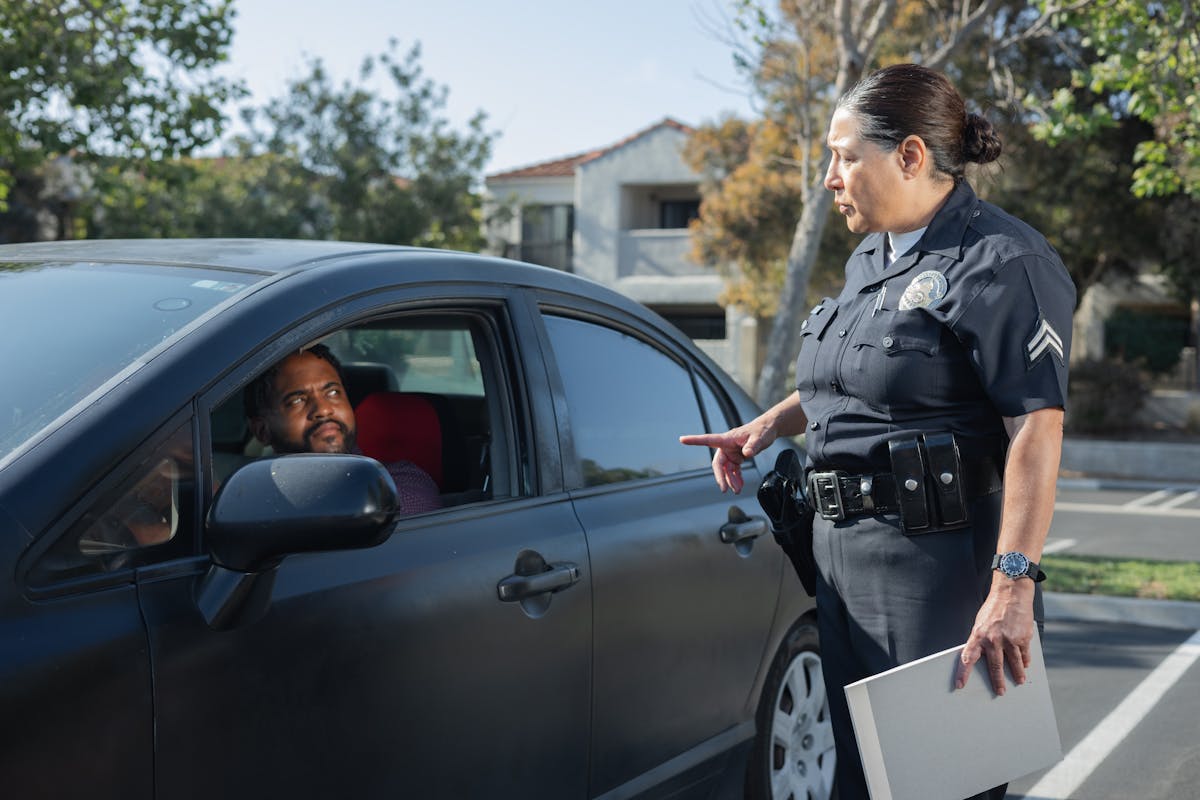 Policewoman Talking to a Man Riding in a Car