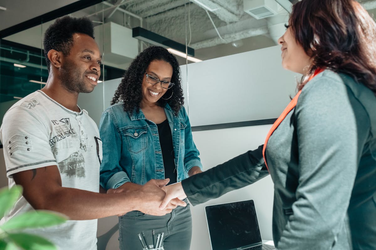 Smiling couple shaking hands with advisor in modern office