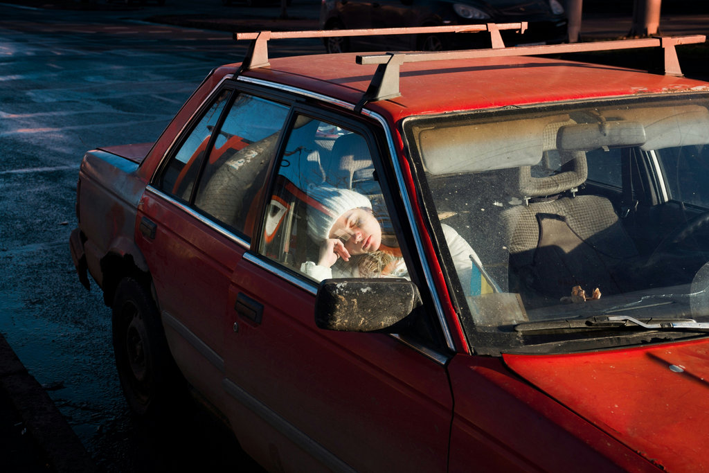 A person is resting inside a red car