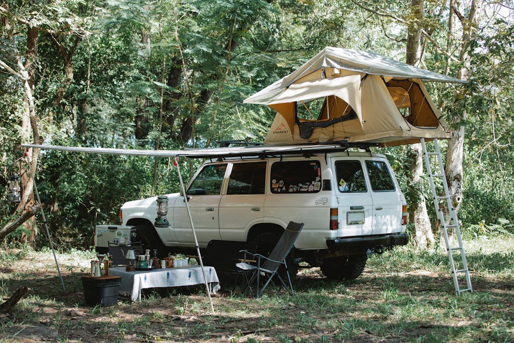 Tent on roof of SUV car parked in woods during camping